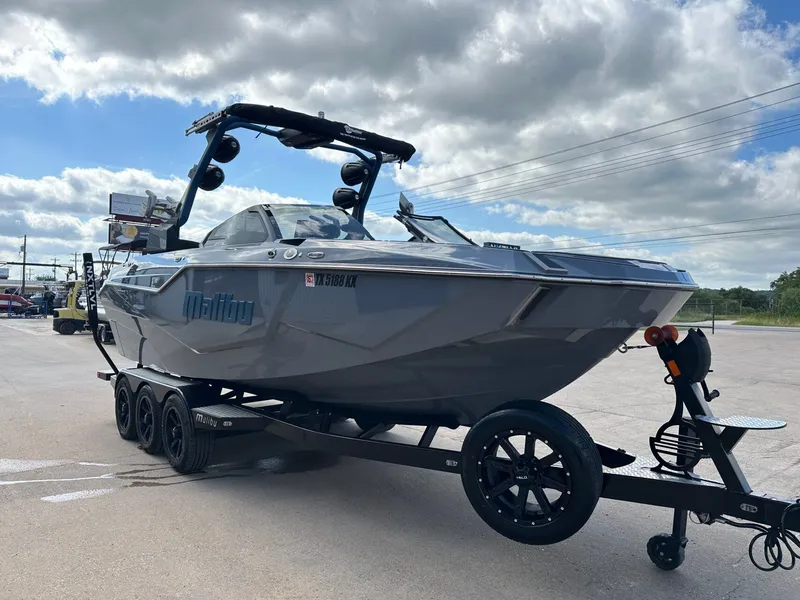 Slide: The Image of 2024 Malibu M242 boat on trailer under cloudy sky. - 7