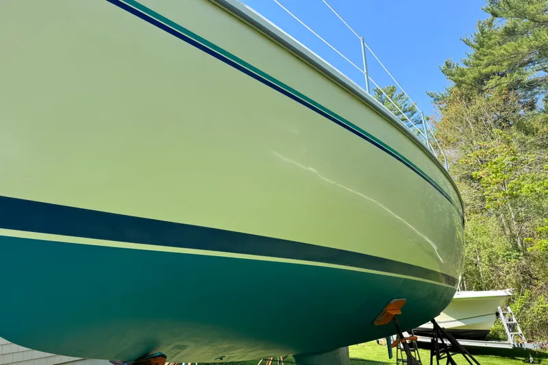 Slide: The Image of 1996 Catalina 36 MkII sailboat hull, green and white, on land with trees in background. - 10