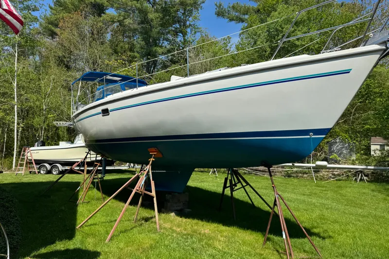 Slide: The Image of 1996 Catalina 36 MkII sailboat on stands in a grassy yard, surrounded by trees. - 11