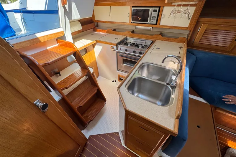 Slide: The Image of Interior of 1996 Catalina 36 MkII yacht featuring kitchen with stove, sink, and wooden cabinetry. - 51