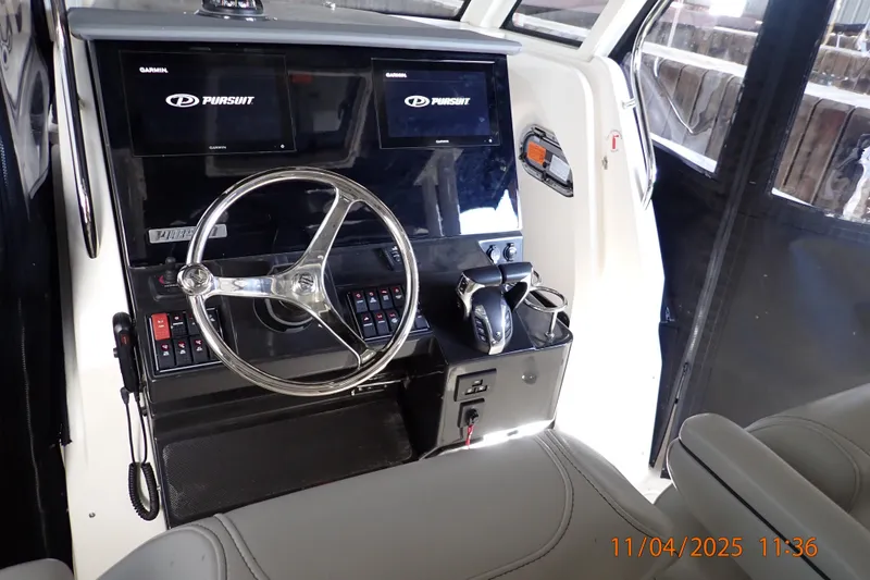 Slide: The Image of 2023 Pursuit S 328 Sport boat helm with dual Garmin displays and steering wheel. - 2