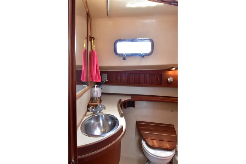 Slide: The Image of 1994 Island Packet 32 yacht bathroom with sink, toilet, and wooden accents. - 12