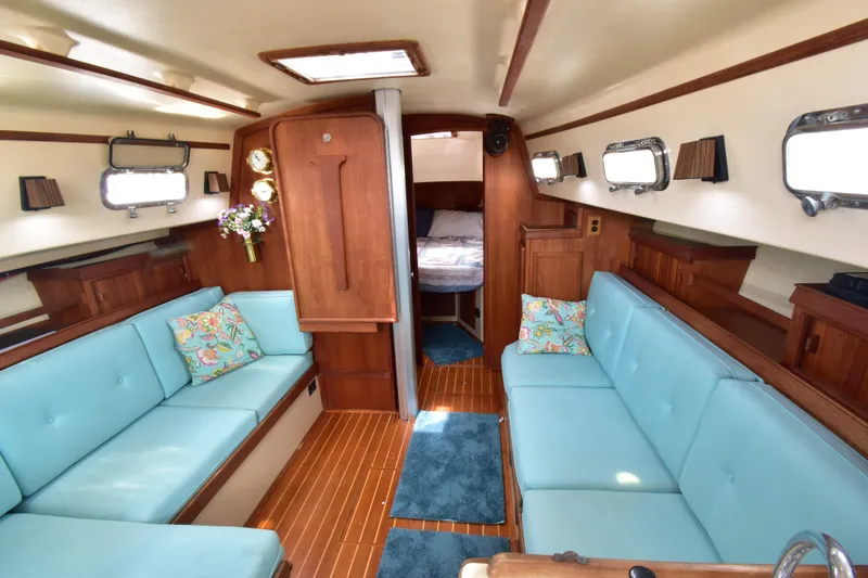 Slide: The Image of Interior of a 1994 Island Packet 32 sailboat with blue seating and wood accents. - 8