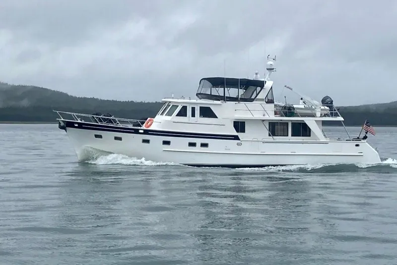 The Image of 1999 Grand Alaskan Pilothouse yacht cruising on calm waters under cloudy skies. - 0