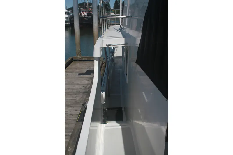 Slide: The Image of 1999 Grand Alaskan Pilothouse yacht docked, showcasing sleek side deck and railing. - 102
