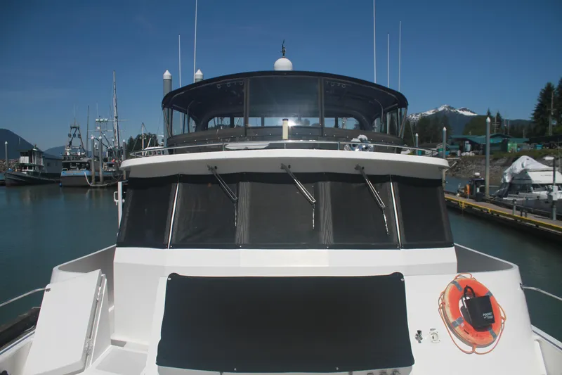 Slide: The Image of 1999 Grand Alaskan Pilothouse yacht docked in a scenic marina with mountains in the background. - 103