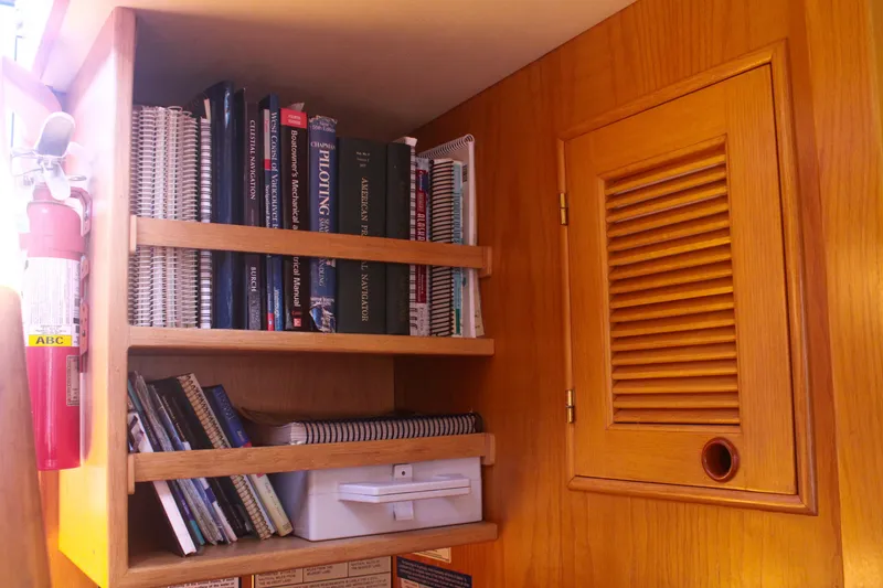 Slide: The Image of Bookshelf with navigation books and fire extinguisher on a 1999 Grand Alaskan Pilothouse. - 106