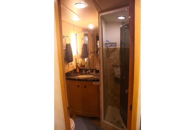 Slide: The Image of 1999 Grand Alaskan Pilothouse bathroom with wooden cabinetry, marble countertop, and glass shower. - 119