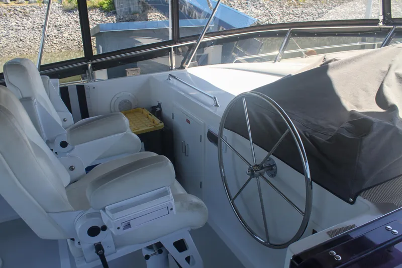 Slide: The Image of 1999 Grand Alaskan Pilothouse interior with steering wheel and white captain chairs. - 155