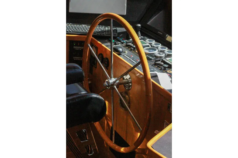 Slide: The Image of 1999 Grand Alaskan Pilothouse helm with wooden steering wheel and control panel. - 171