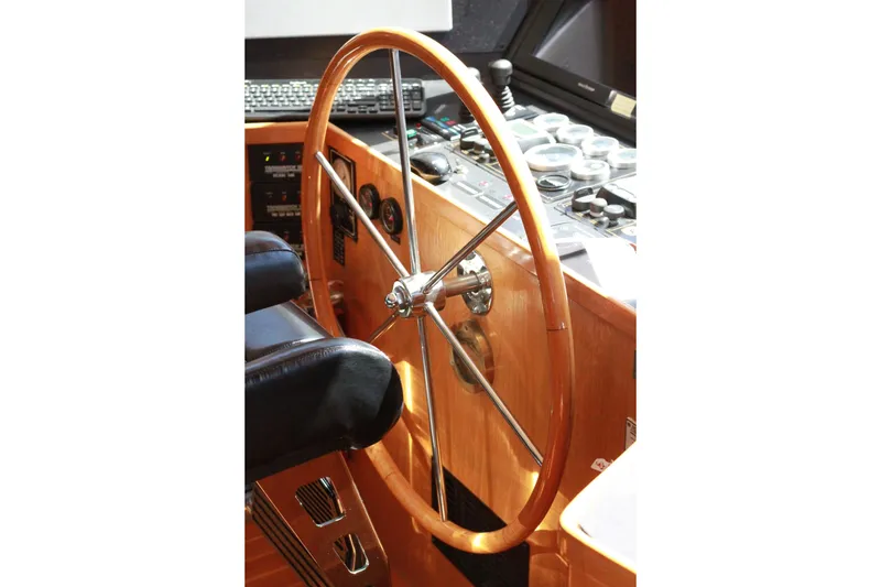 Slide: The Image of Pilothouse steering wheel of a 1999 Grand Alaskan boat, featuring wooden and metal design. - 172