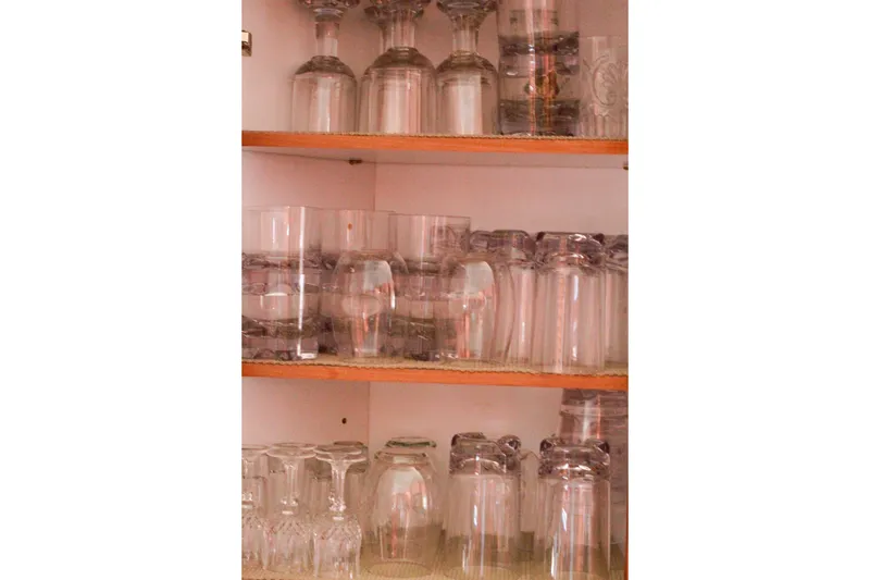 Slide: The Image of Glassware neatly arranged on wooden shelves inside a cabinet. - 185