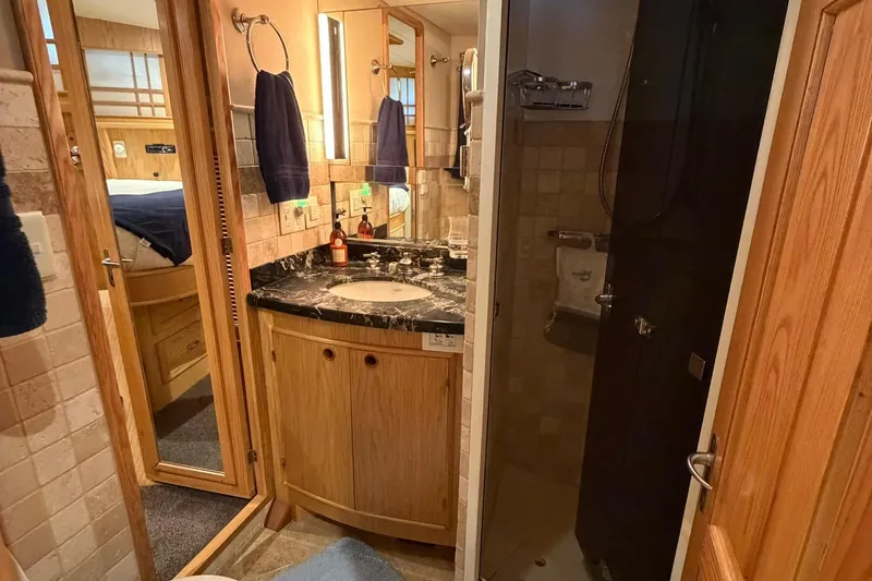Slide: The Image of Luxurious bathroom in a 1999 Grand Alaskan Pilothouse yacht, featuring elegant wood and marble finishes. - 19