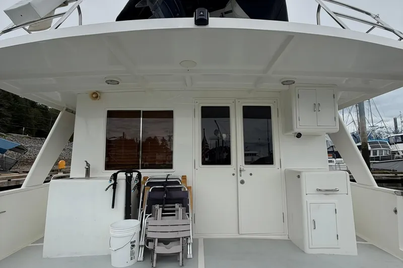 Slide: The Image of 1999 Grand Alaskan Pilothouse yacht deck with chairs, storage, and marina view. - 27