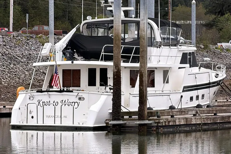 Slide: The Image of 1999 Grand Alaskan Pilothouse yacht docked, featuring "Knot to Worry" name and American flag. - 29