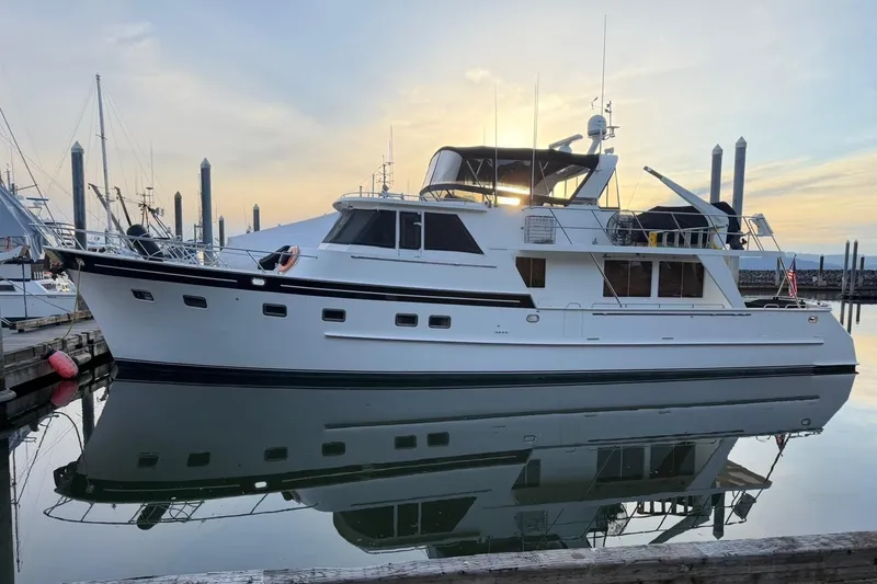 Slide: The Image of 1999 Grand Alaskan Pilothouse yacht docked at sunset, reflecting on calm water. - 44
