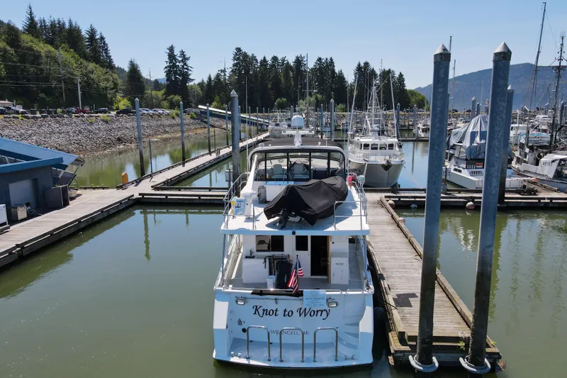 Slide: The Image of Grand Alaskan Pilothouse 1999 yacht docked at marina, surrounded by boats and lush greenery. - 67