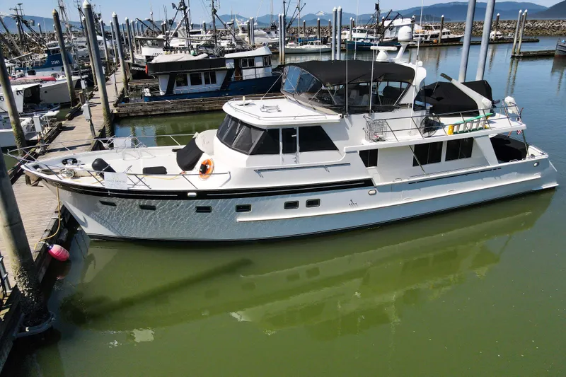 Slide: The Image of 1999 Grand Alaskan Pilothouse yacht docked in a marina, surrounded by other boats. - 68