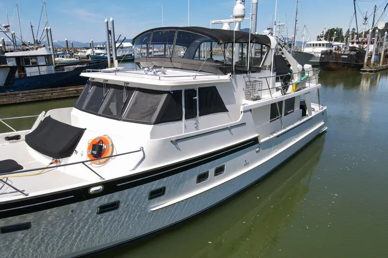 Slide: The Image of 1999 Grand Alaskan Pilothouse yacht docked in a marina, featuring sleek design and spacious deck. - 74