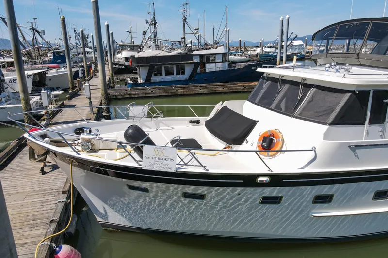 Slide: The Image of 1999 Grand Alaskan Pilothouse yacht docked at marina with other boats in background. - 75