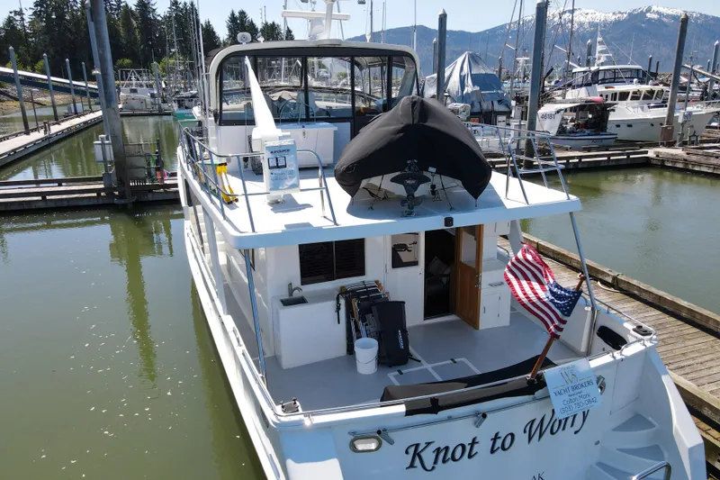 Slide: The Image of 1999 Grand Alaskan Pilothouse yacht docked, featuring American flag and "Knot to Worry" name. - 77