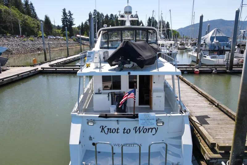 Slide: The Image of 1999 Grand Alaskan Pilothouse yacht docked in marina, named "Knot to Worry." - 79