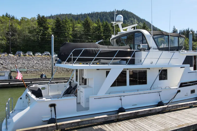 Slide: The Image of 1999 Grand Alaskan Pilothouse yacht docked, featuring sleek design and spacious upper deck. - 80