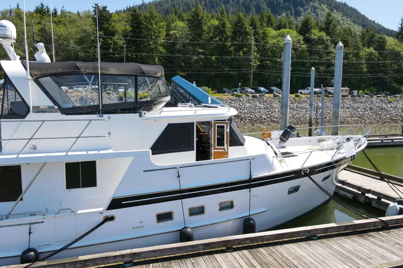 Slide: The Image of 1999 Grand Alaskan Pilothouse yacht docked at marina with forested background. - 82