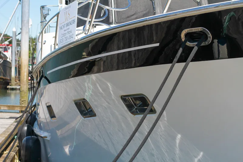 Slide: The Image of 1999 Grand Alaskan Pilothouse yacht docked with ropes, reflecting sunlight on water. - 86