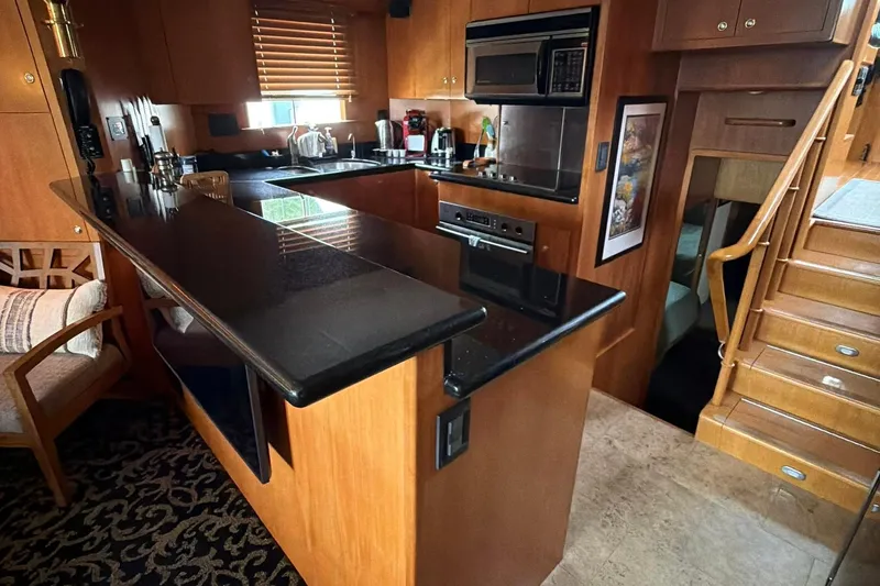 Slide: The Image of Luxurious 1999 Grand Alaskan Pilothouse kitchen with sleek black countertops and wooden cabinetry. - 9