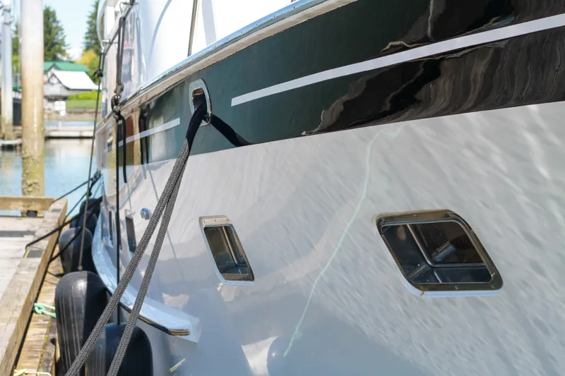Slide: The Image of 1999 Grand Alaskan Pilothouse yacht docked, showcasing sleek design and portholes. - 91
