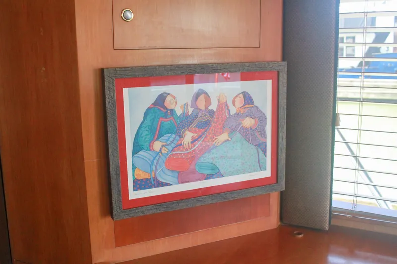 Slide: The Image of Framed artwork inside 1999 Grand Alaskan Pilothouse, featuring colorful figures, near window blinds. - 97