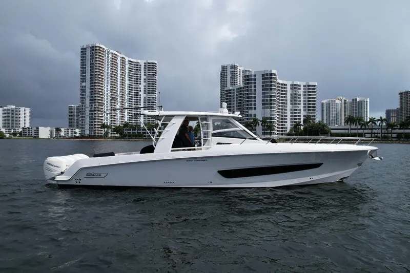 Slide: The Image of 2020 Boston Whaler 420 Outrage boat cruising near city skyline on a cloudy day. - 2