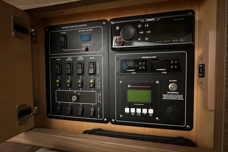 Slide: The Image of Control panel inside a 2020 Boston Whaler 420 Outrage, featuring battery and generator controls. - 37