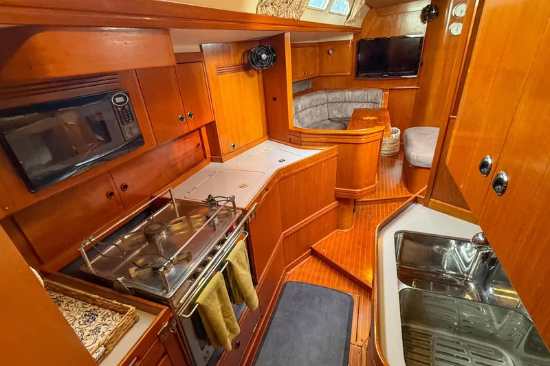 Slide: The Image of Luxurious 1990 Baltic 52 yacht interior with wooden cabinetry, kitchen, and cozy seating area. - 28