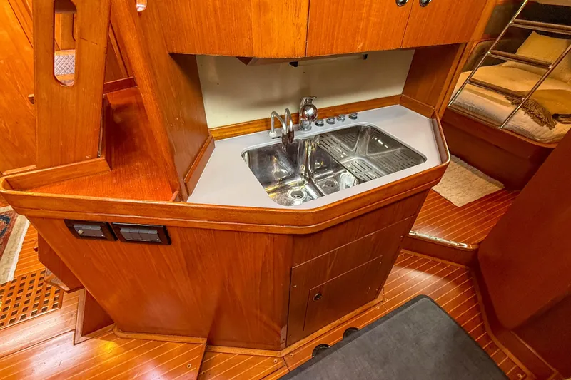 Slide: The Image of Wooden interior of a 1990 Baltic 52 yacht featuring a compact kitchen sink area. - 30