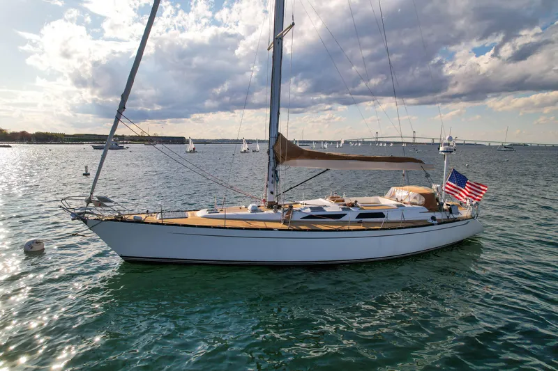 Slide: The Image of Sailing yacht Baltic 52 (1990) on calm waters with American flag, under a partly cloudy sky. - 60