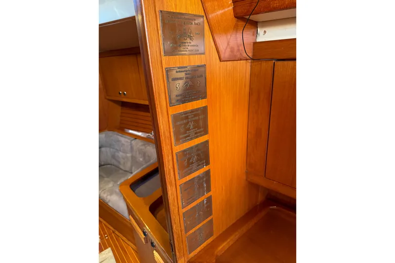 Slide: The Image of Interior of a 1990 Baltic 52 yacht showcasing wooden paneling and engraved plaques. - 50