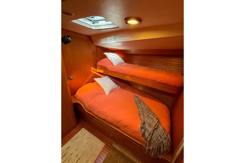 Slide: The Image of Cozy cabin with bunk beds in a 1990 Baltic 52 yacht, featuring warm lighting and orange bedding. - 22