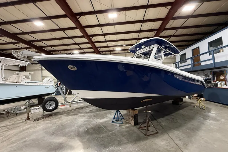 Slide: The Image of 2012 Everglades 275 Center Console boat in indoor storage, blue hull, elevated on stands. - 2