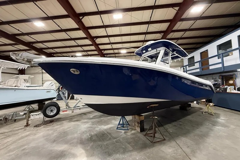 Slide: The Image of 2012 Everglades 275 Center Console boat in indoor storage, blue hull, elevated on stands. - 3