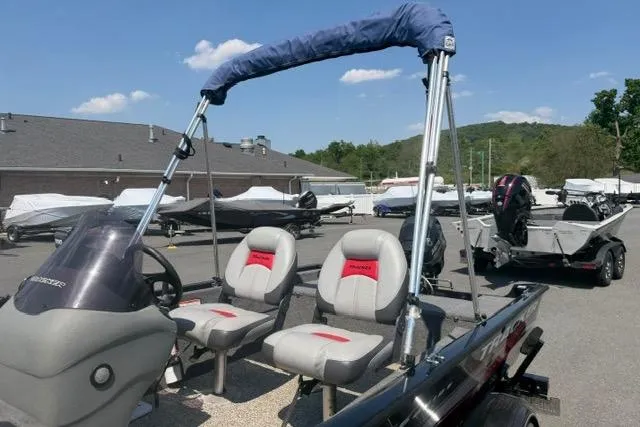 Slide: The Image of 2015 Tracker Super Guide V-16 SC boat with seating, parked outdoors under a clear sky. - 10
