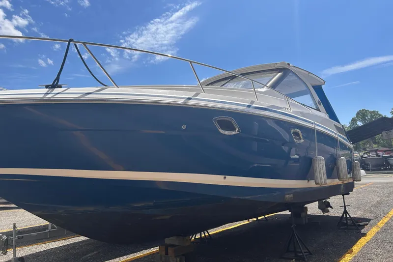 The Image of 2017 Regal 35 Sport Coupe boat on stands under a clear blue sky. - 0