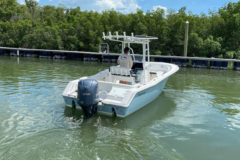 Slide: The Image of 2023 Tidewater 220 LXF boat cruising in calm waters near lush greenery. - 15