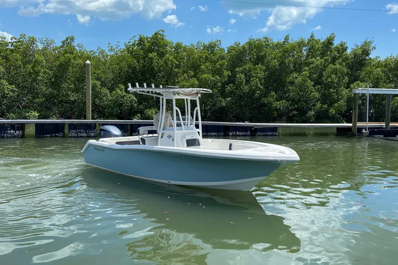 Slide: The Image of 2023 Tidewater 220 LXF boat on calm water, surrounded by lush greenery and clear blue sky. - 2