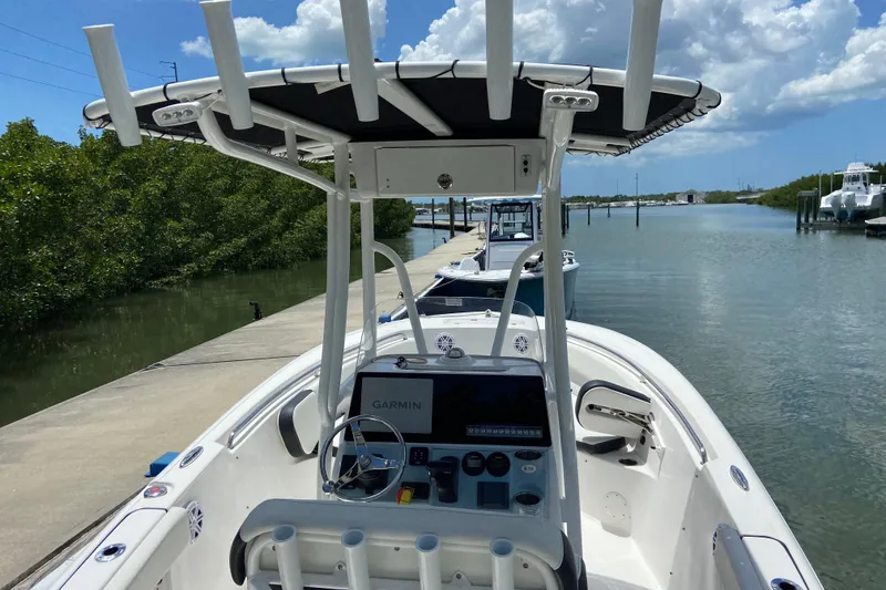 Slide: The Image of 2023 Tidewater 220 LXF boat docked by a scenic waterway under a cloudy sky. - 23