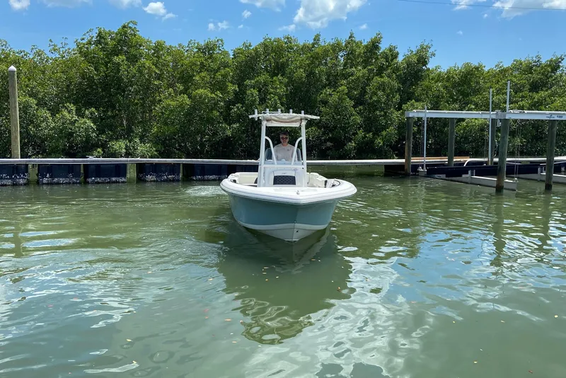 Slide: The Image of 2023 Tidewater 220 LXF boat navigating calm waters near a dock. - 4