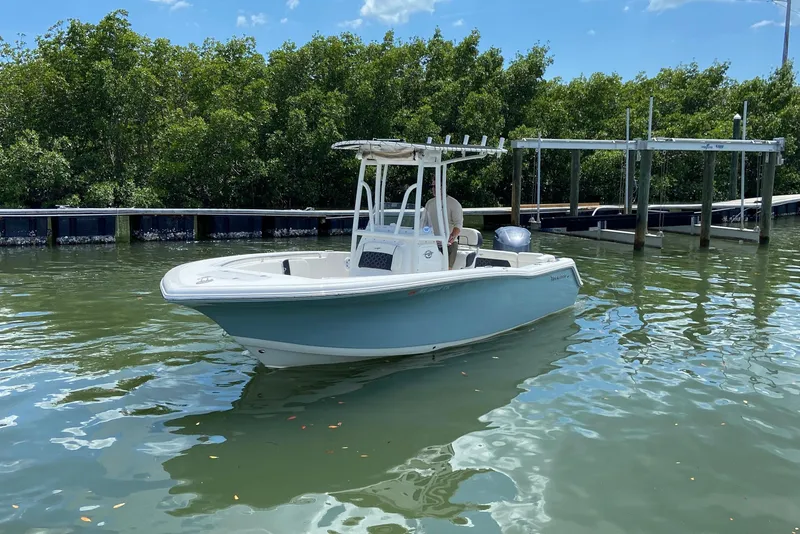 Slide: The Image of 2023 Tidewater 220 LXF boat on calm water near a dock, surrounded by greenery. - 6