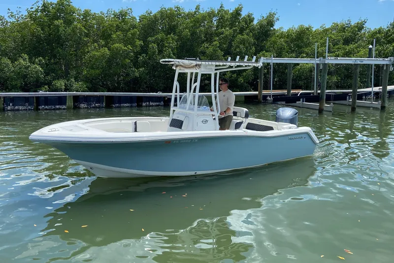 Slide: The Image of 2023 Tidewater 220 LXF boat cruising on calm water near a dock. - 7