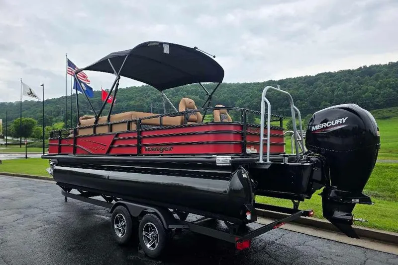 Slide: The Image of 2026 Ranger 220F pontoon boat with Mercury engine on a trailer, flags in the background. - 2